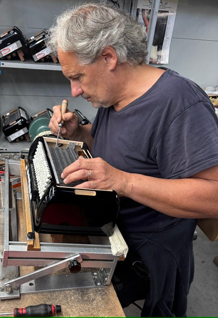 Accordion technician carrying out detailed repair work on a button accordion