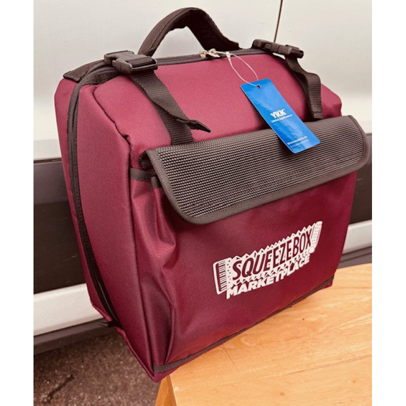 Burgundy bag with a blue tag and 'Squeezebox Marketplace' branding on a wooden surface.