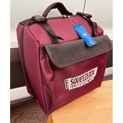 Burgundy bag with a blue tag and 'Squeezebox Marketplace' branding on a wooden surface.